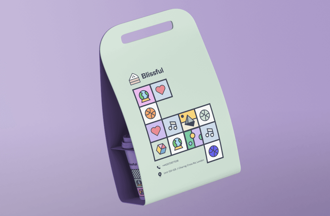 A sage cup carrier with a cut-out handle, tiles down the front and a lilac cup tucked inside.